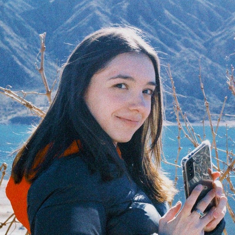 A woman is holding a camera in front of her face.