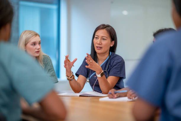 A group of nurses are sitting around a table having a meeting.