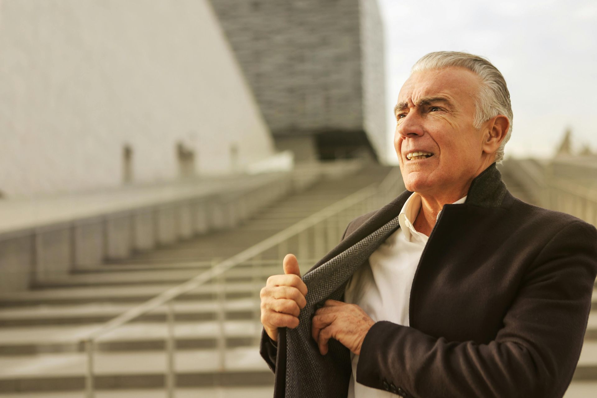 An older man in a suit is taking off his jacket.