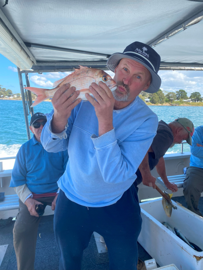 Man proudly holding a freshly caught fish while standing on a boat