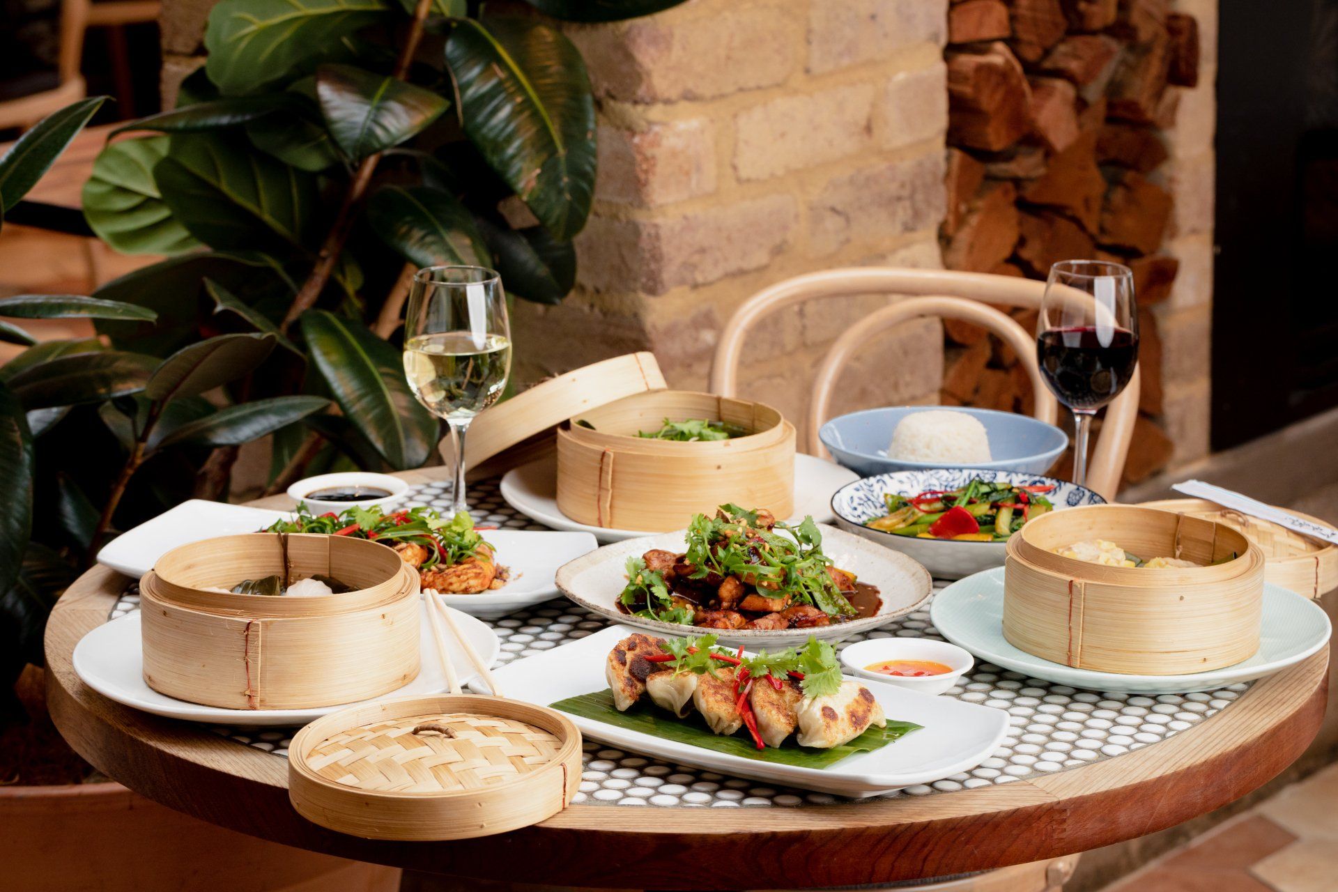 Shared Wok O’clock dining table with bamboo steamers, Asian-style dishes and wine in a relaxed restaurant setting