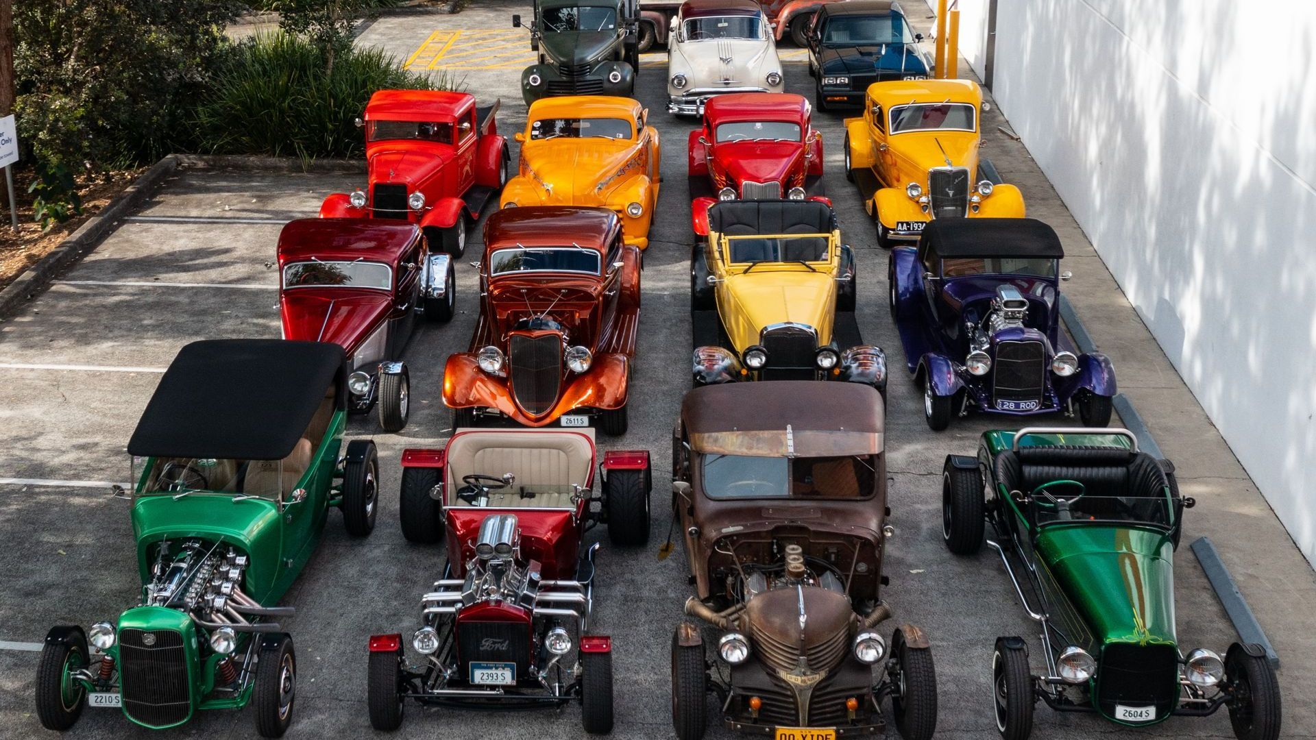 Row of brightly coloured hot rods parked outdoors during a club display