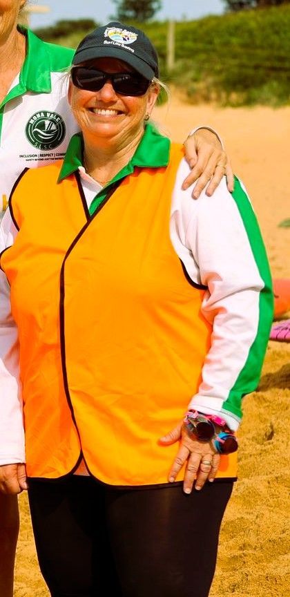 Lexi Le’Blang smiling on the beach while wearing green lifesaving uniform