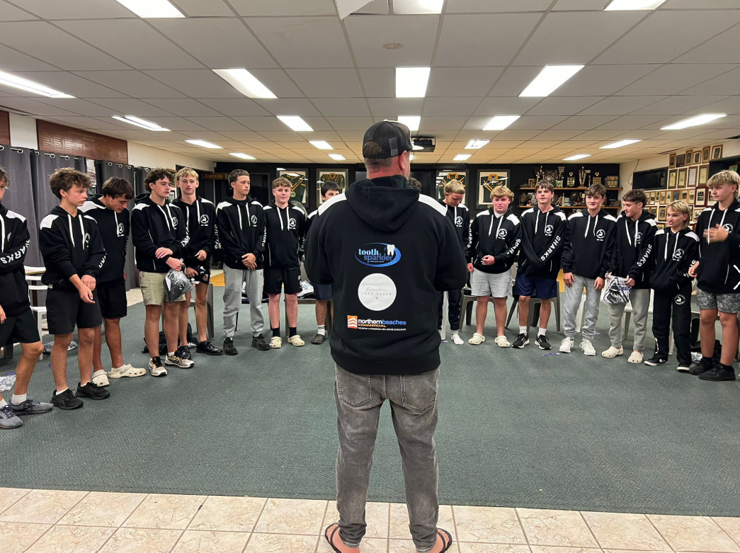 Coach speaking to junior players gathered in an indoor team meeting room