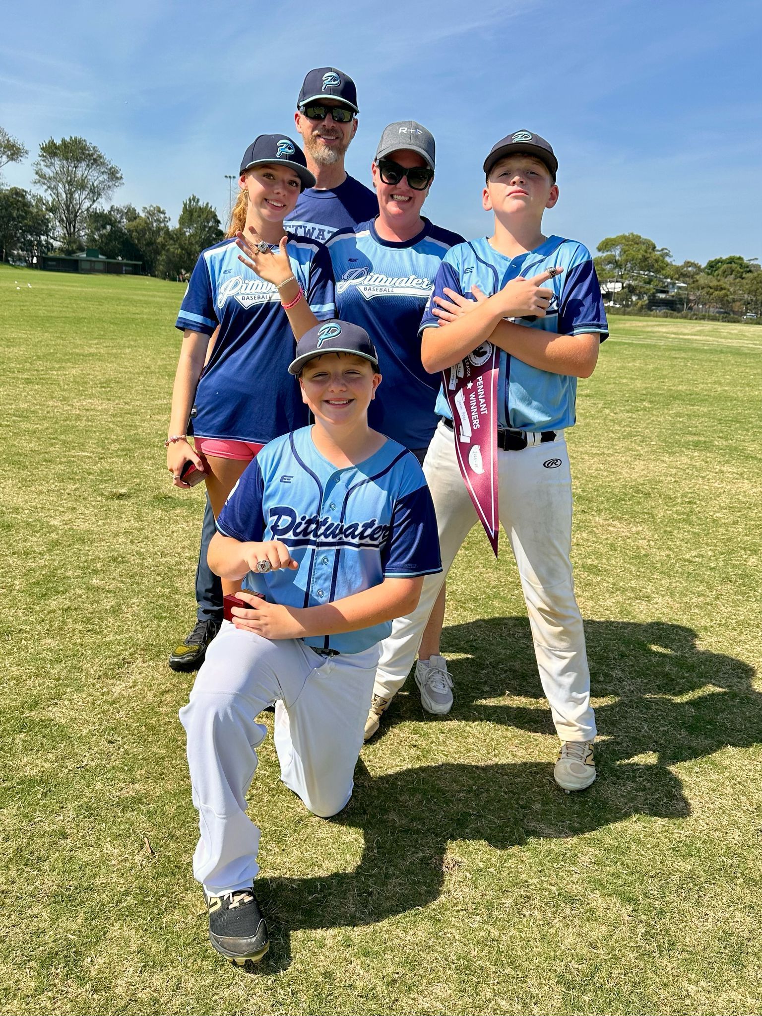 A family smiling on a sports field wearing matching blue rugby jerseys