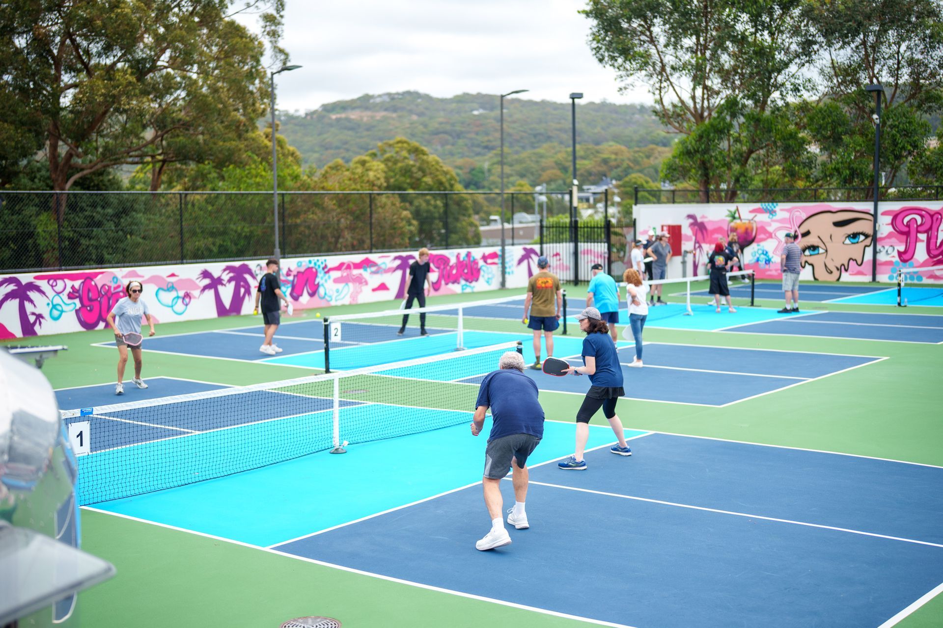 Players enjoying pickleball matches on colourful outdoor community courts at a Northern Beaches venue