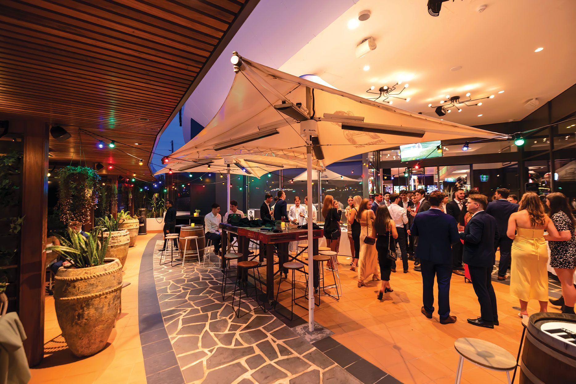 Guests gathering under a large outdoor canopy during an evening event at Mona Vale