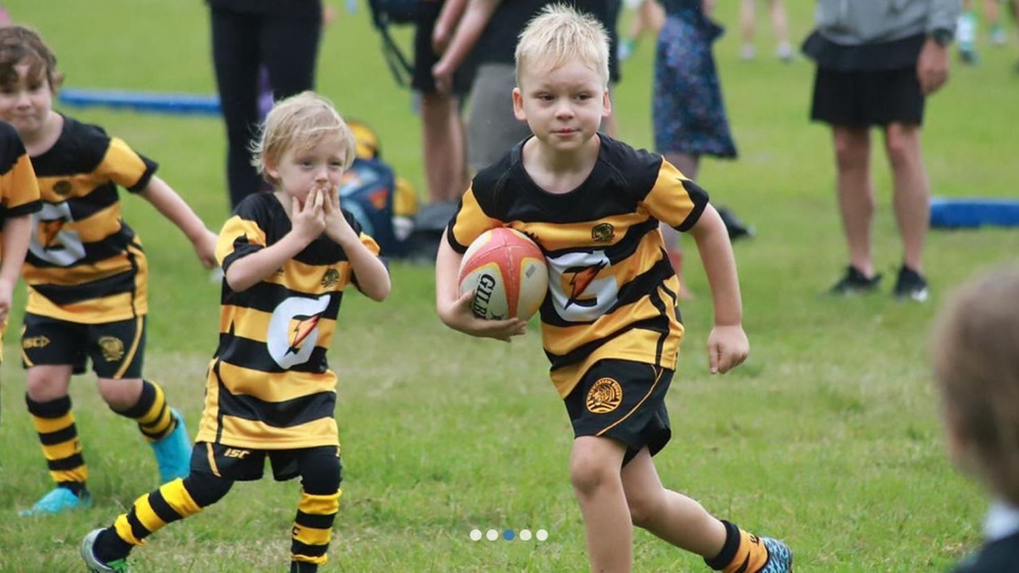 Children playing junior rugby for Narrabeen Tigers Rugby Club on a grass field