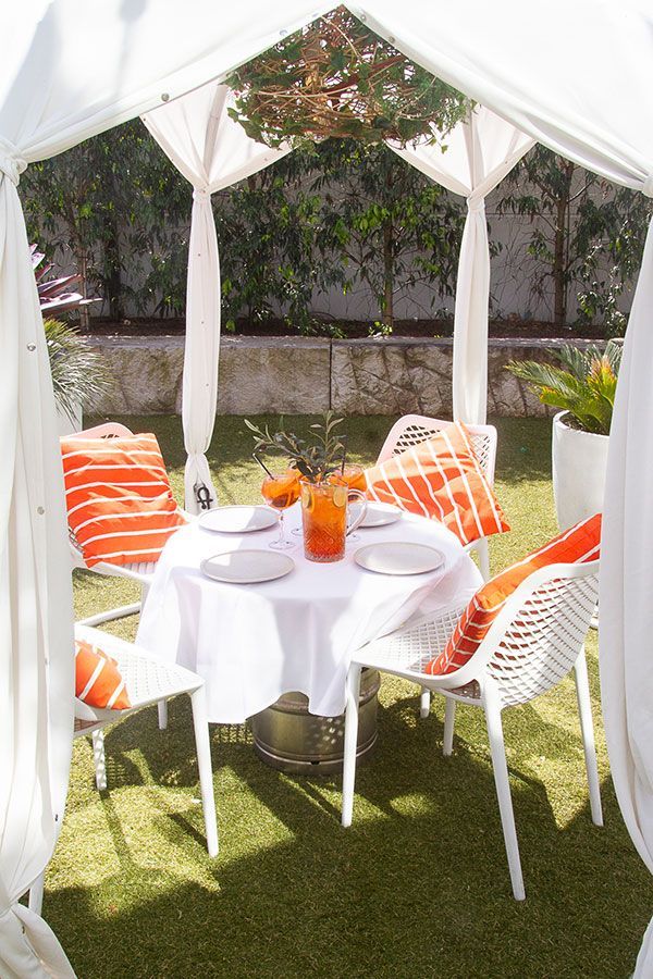 Elegant white cabana with lush green backdrop available for premium event packages