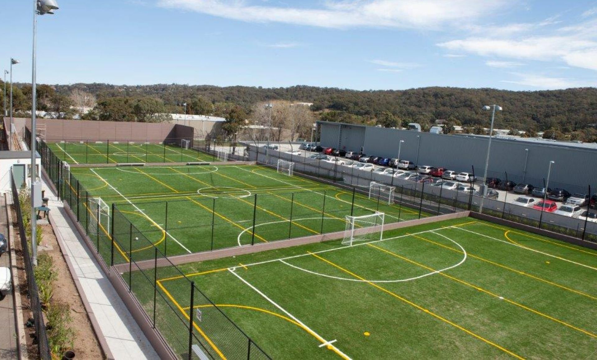 Aerial view of several outdoor futsal fields beside large commercial buildings