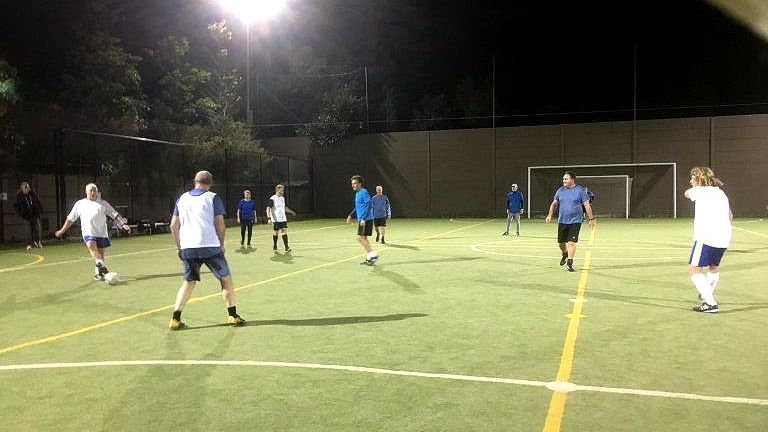 Walking football game in progress on an outdoor futsal court at night