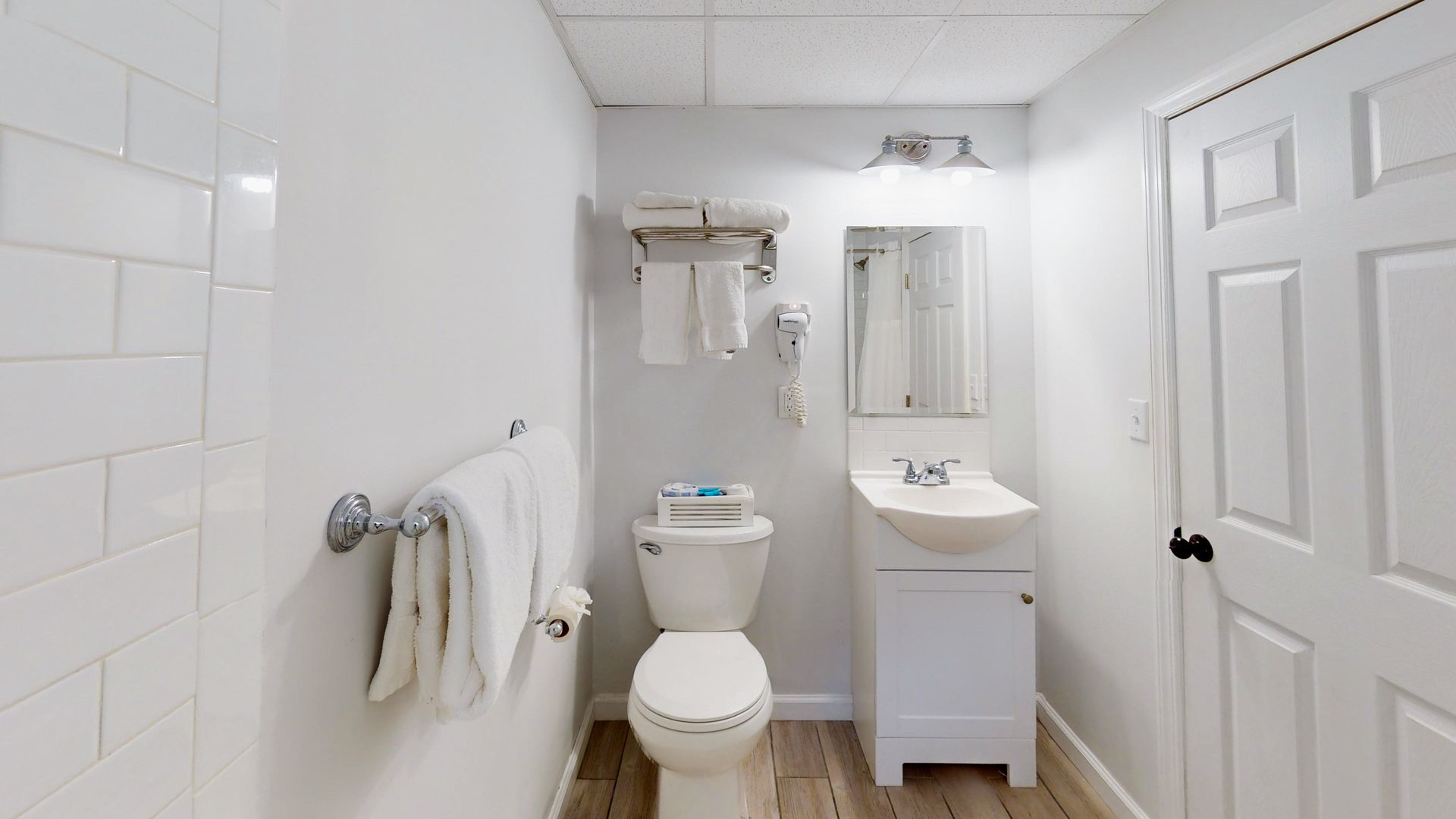 A bathroom with a toilet , sink and mirror.