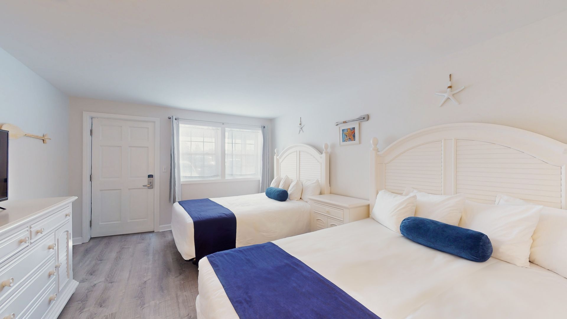 A hotel room with two beds , a dresser and a television.