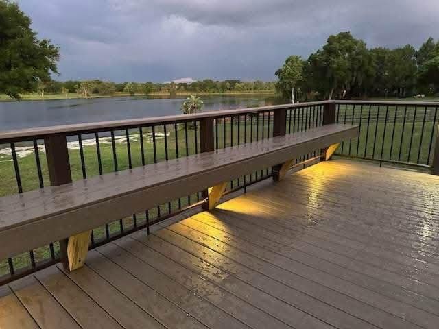 Wooden deck bench overlooking a river at dusk, with warm under-bench lighting and railings.