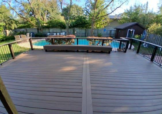 Backyard wooden deck overlooking a swimming pool, trees, and a small shed