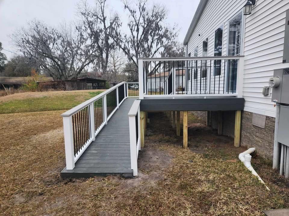 Back deck with a wheelchair ramp and white railing beside a house