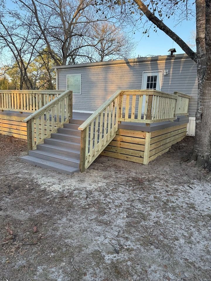 Wooden wheelchair ramp with railings leading to a beige house in a yard.