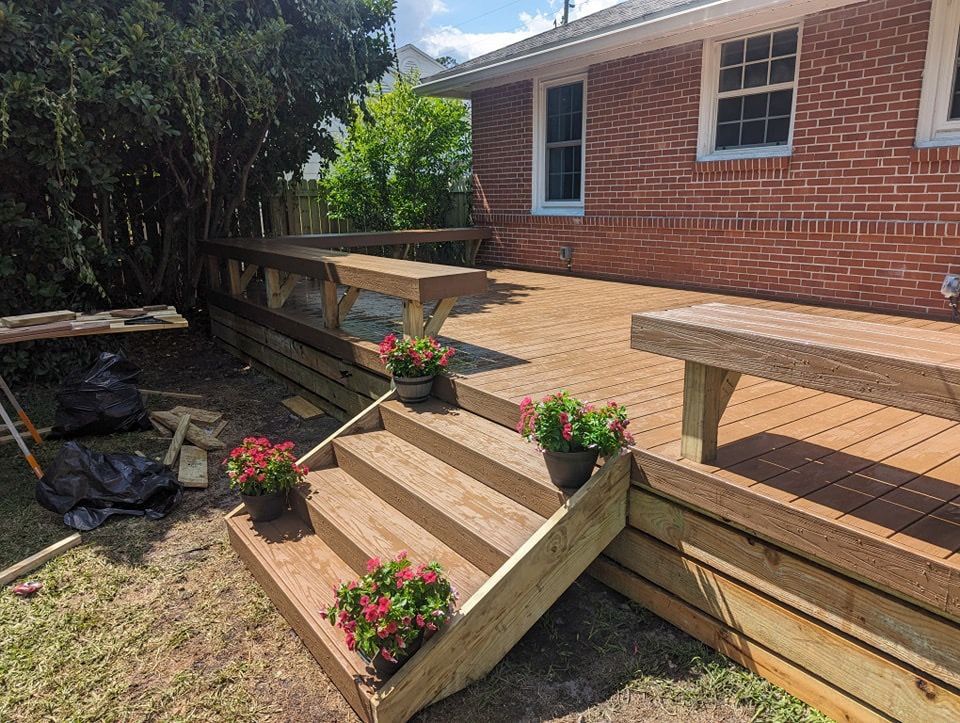 Backyard wooden deck stairs with flower planters beside a red brick house