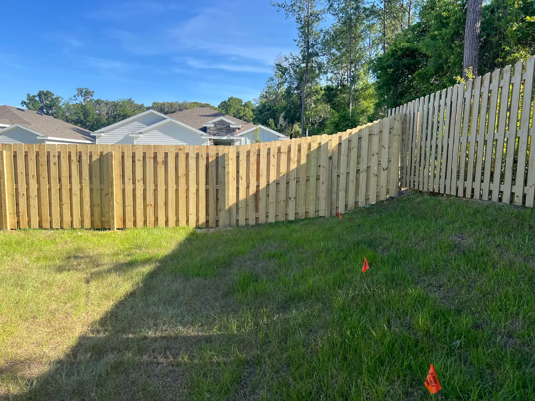 Backyard with green grass and a wooden privacy fence under clear blue sky