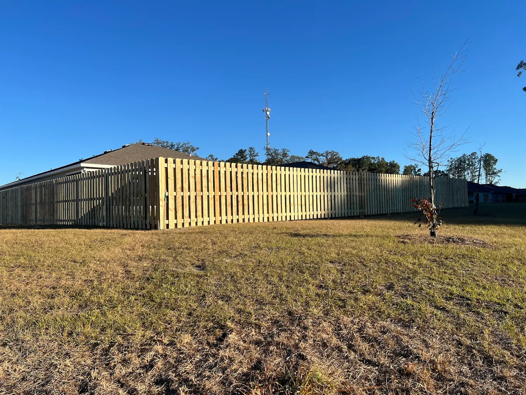 Large fenced building under construction in a grassy field on a sunny day
