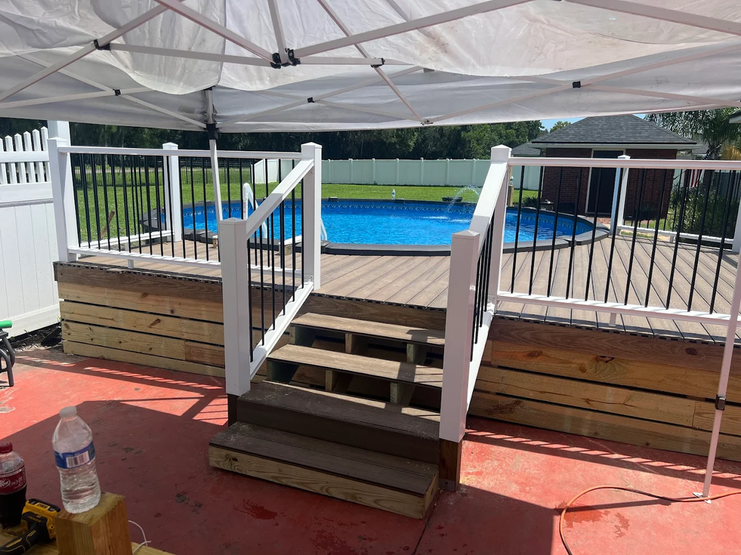 Backyard deck steps under a canopy, with white railings and an above-ground pool in the background