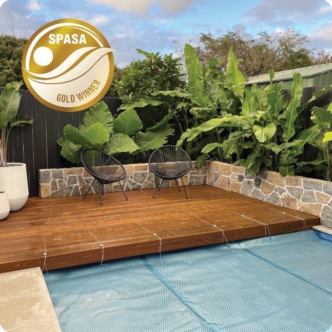 Poolside deck with seating, bordered by stone walls and lush greenery; SPASA Gold Winner seal.