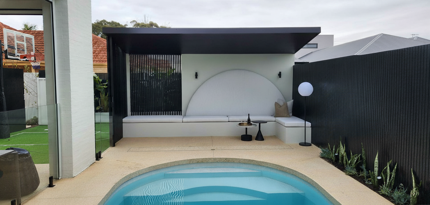 Backyard pool area with white lounge seating, black privacy fence, and a pergola.