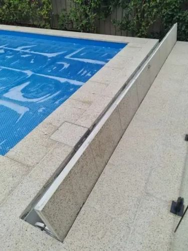 Poolside with a blue cover, a water overflow channel along the edge.