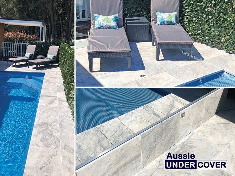 Poolside scene with lounge chairs, blue pool, and stone tiling.