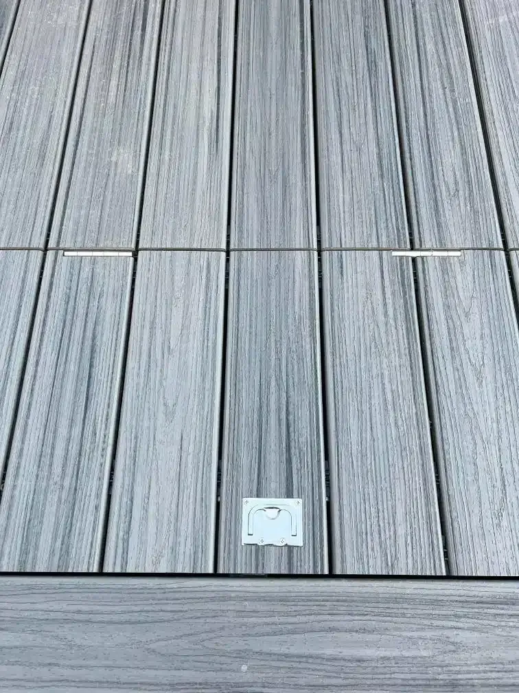 Gray wood deck with a rectangular access panel in the center.