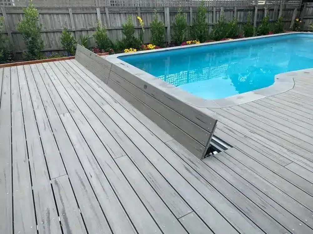 Pool deck with gray composite boards and a pool with blue water.