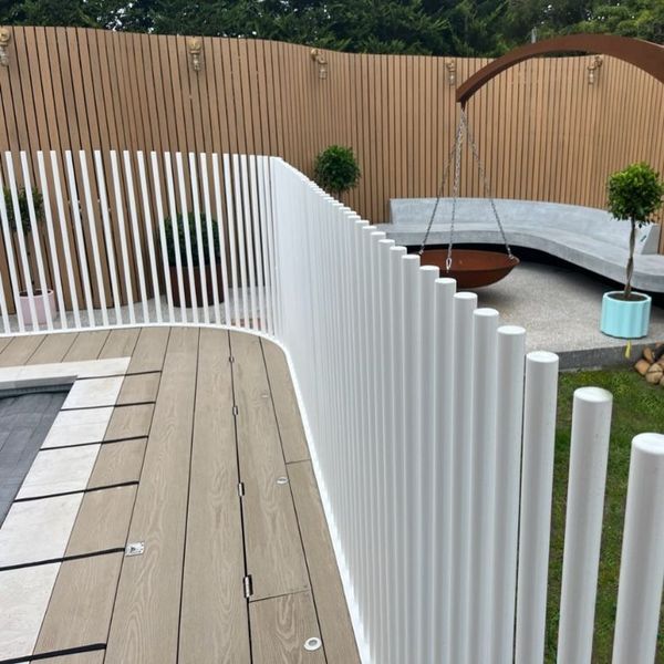 White vertical fence on a deck, with a wood background and outdoor seating area.