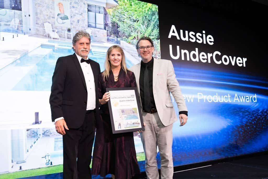Three people holding an award, with
