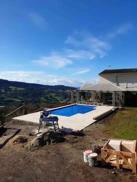 Pool area with blue sky, pool, house, and scenic mountain view.