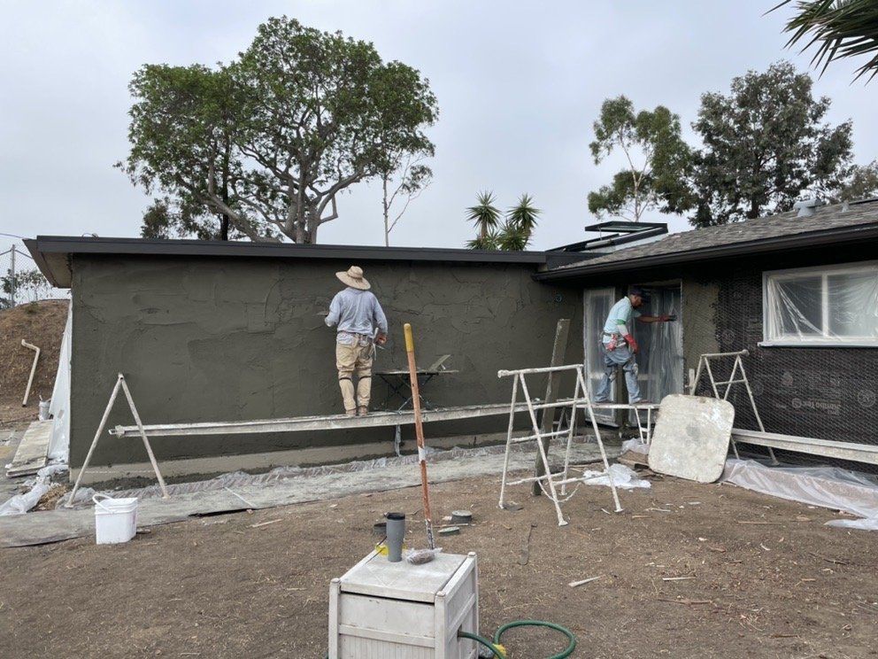 Two men are working on the side of a house.