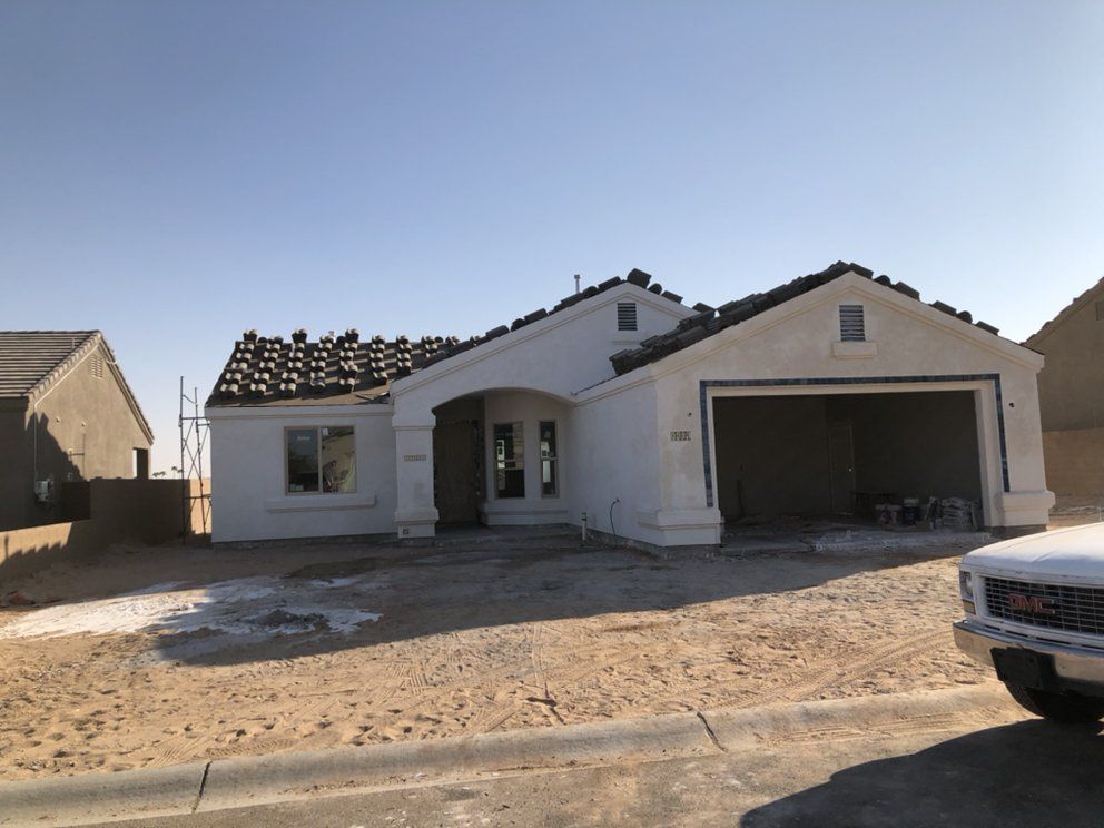 A white truck is parked in front of a house under construction