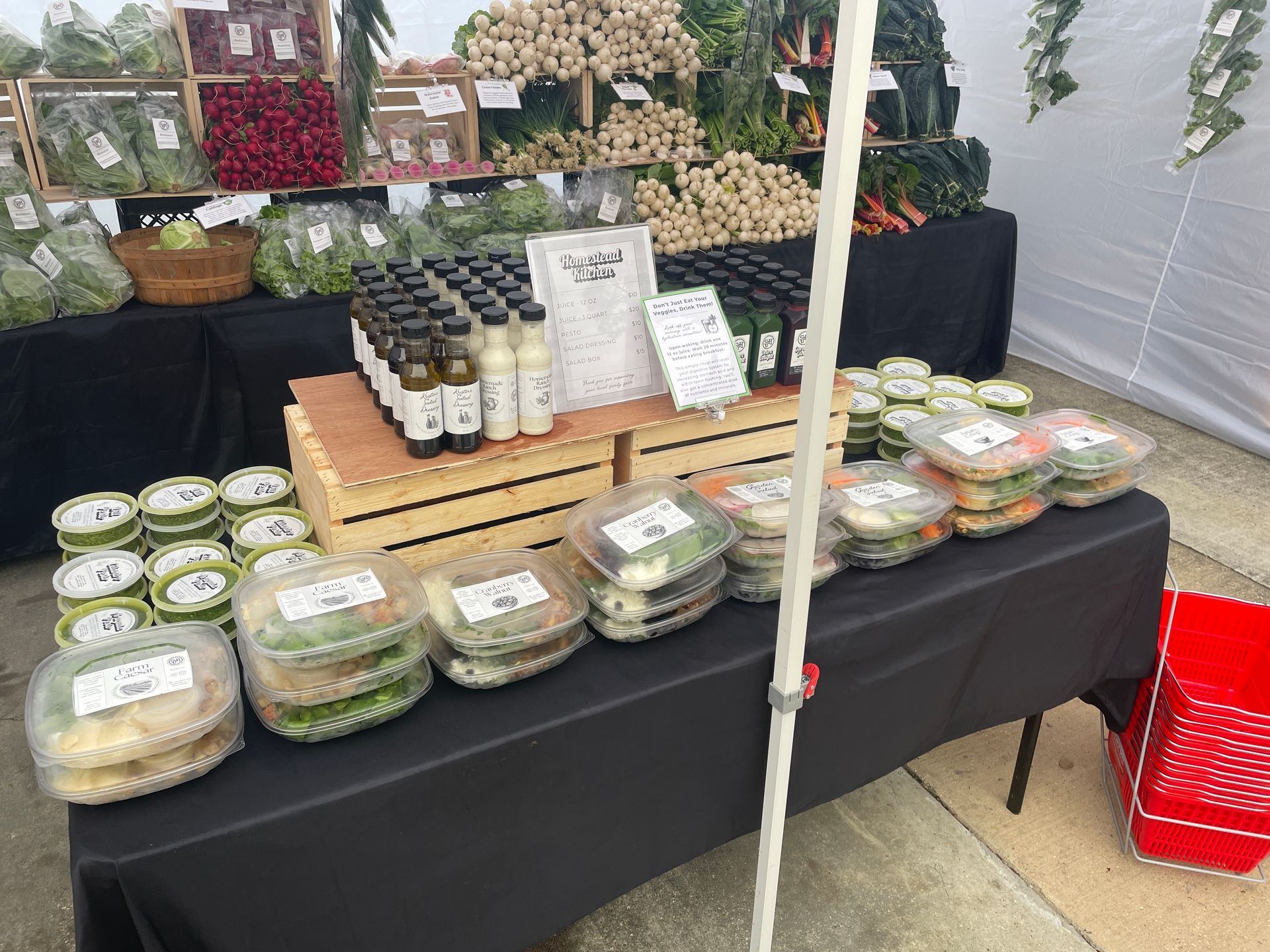 Market stall with packaged salads and bottled drinks on a black table under a tent