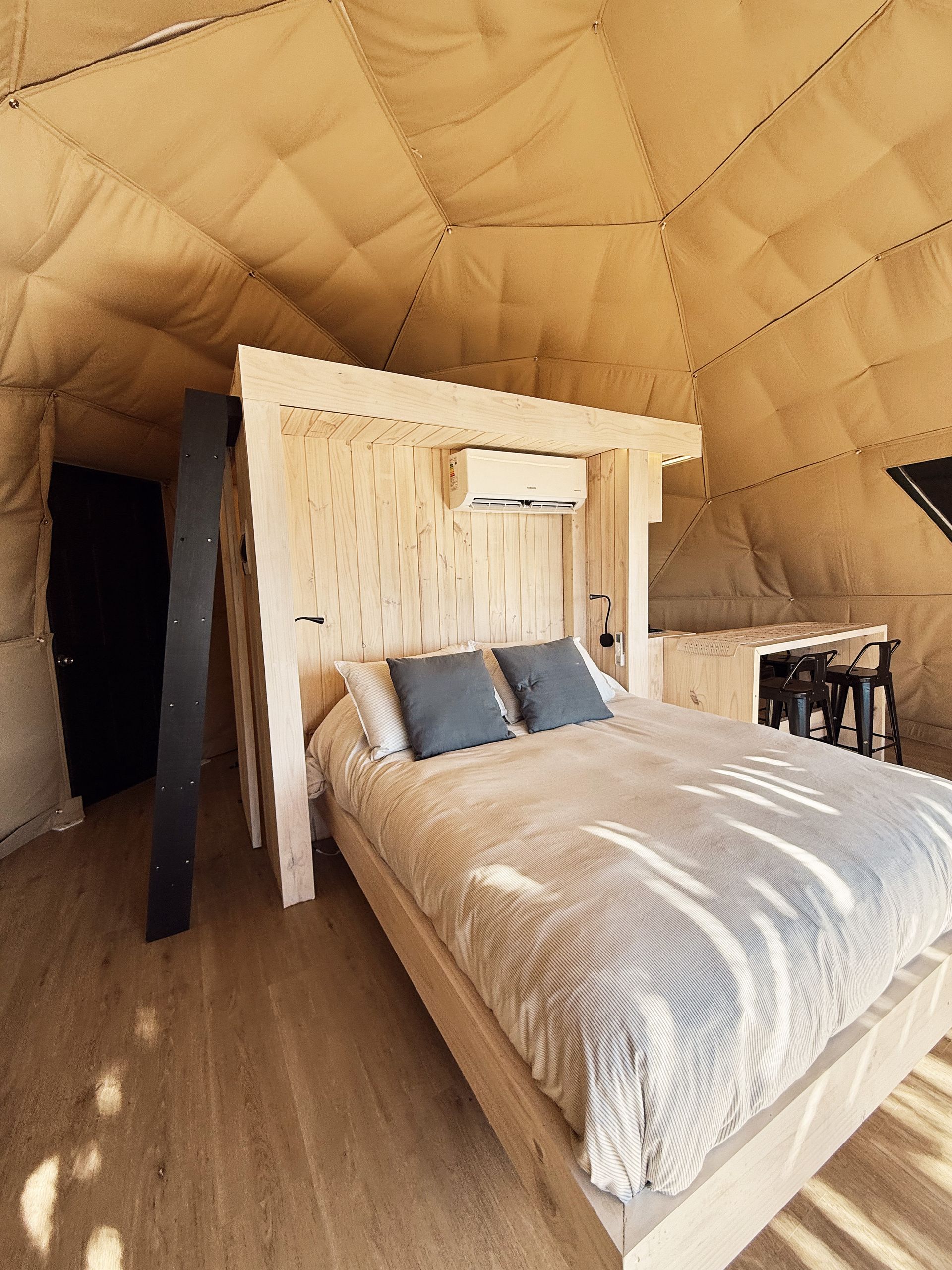 Interior de domo con camas, cocina y baño, y aire acondicionado