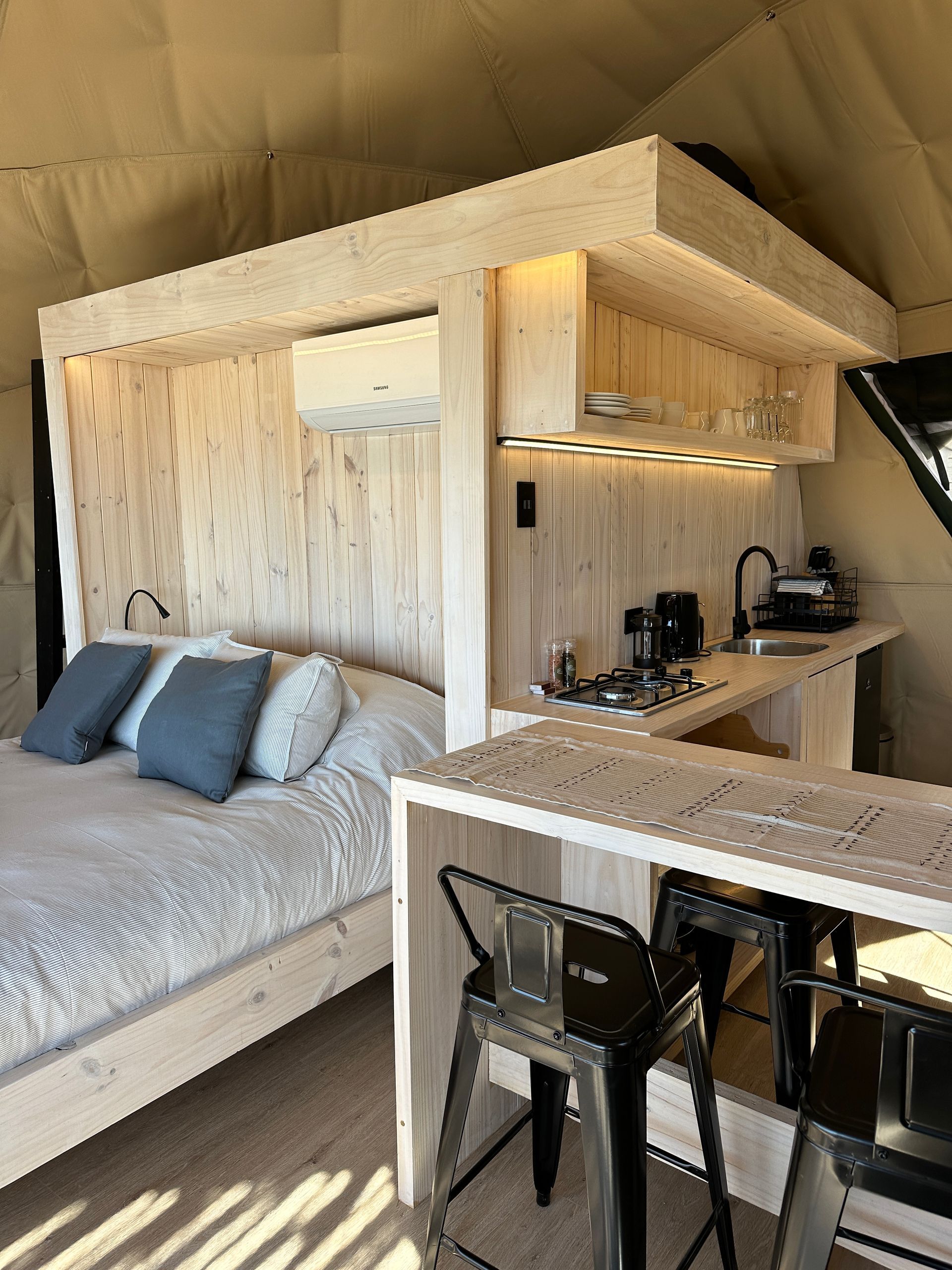 Interior de domo con cama premium, cocina, aire acondicionado