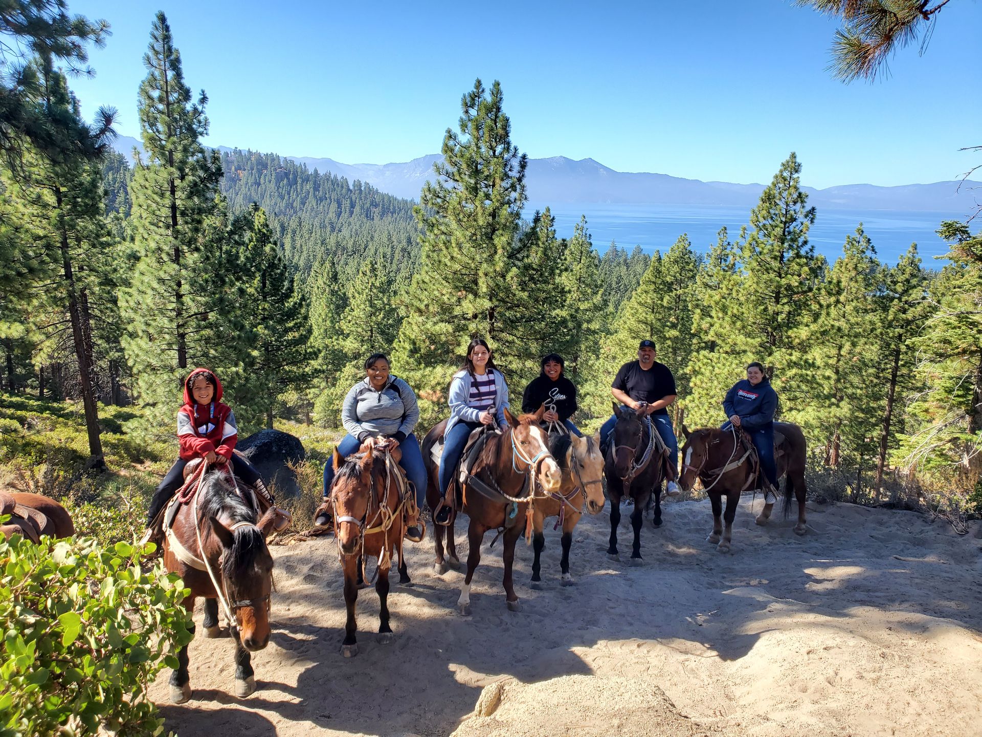 A group of people are riding horses on a dirt road.