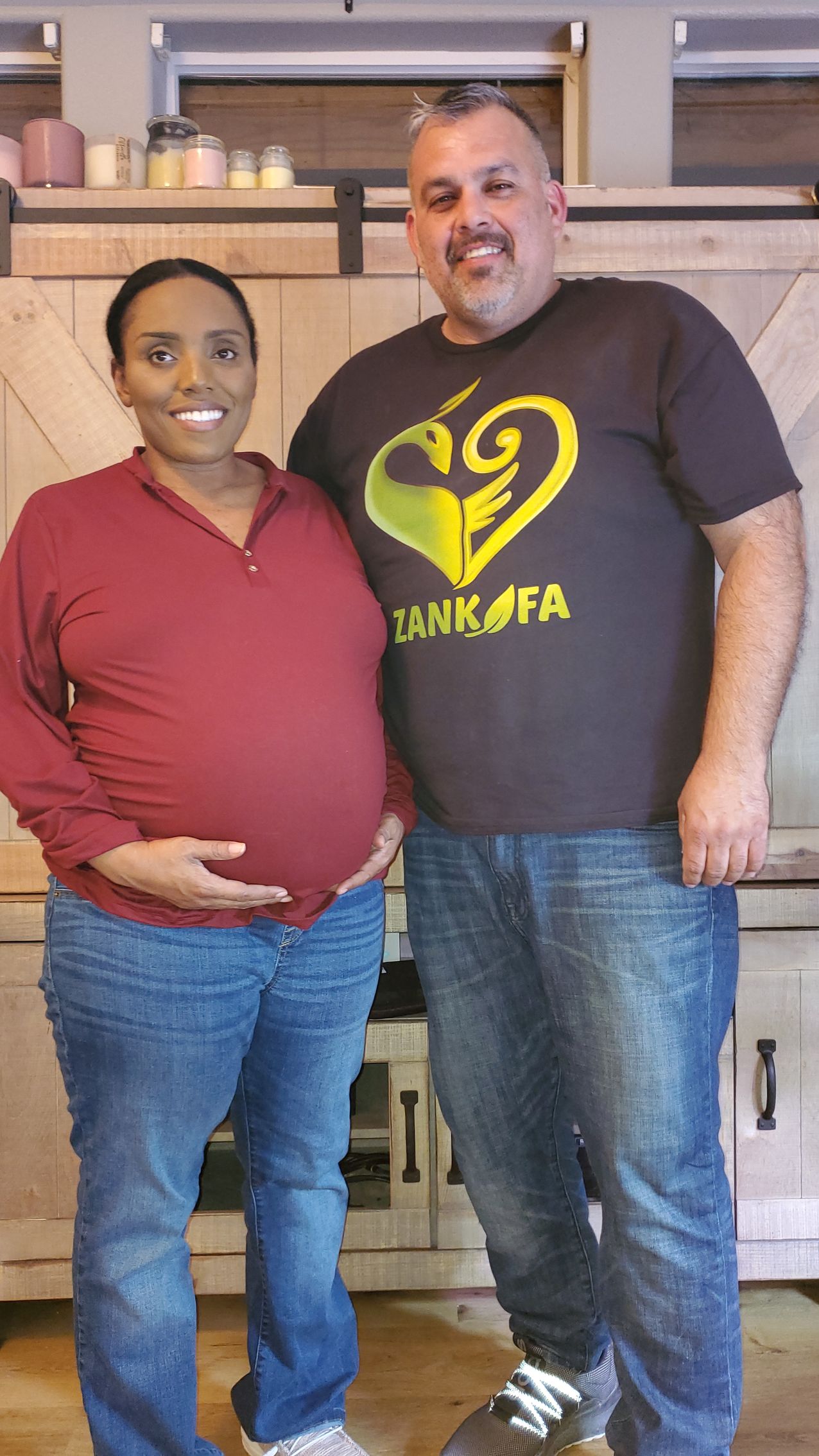 A man and a pregnant woman are posing for a picture in a kitchen.