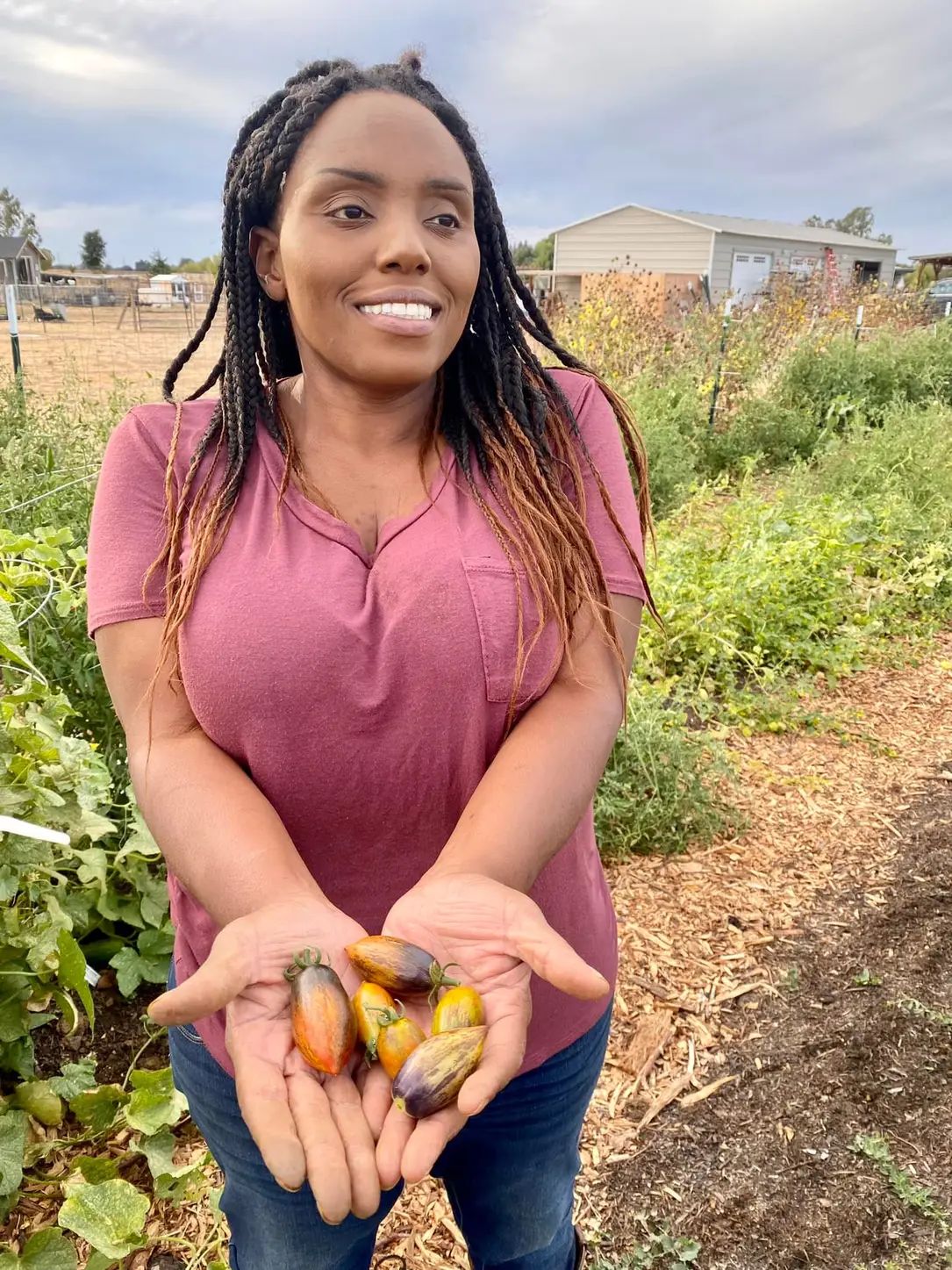 A woman is holding a bunch of vegetables in her hands.