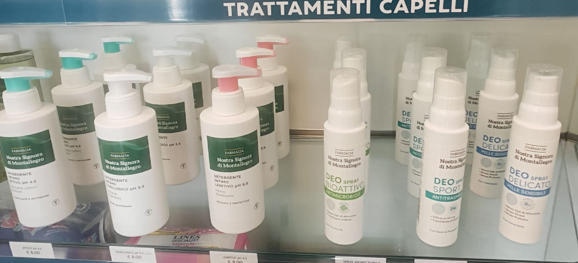 Scaffale espositivo con flaconi bianchi per trattamenti per capelli e dispenser a pompa sotto l'insegna