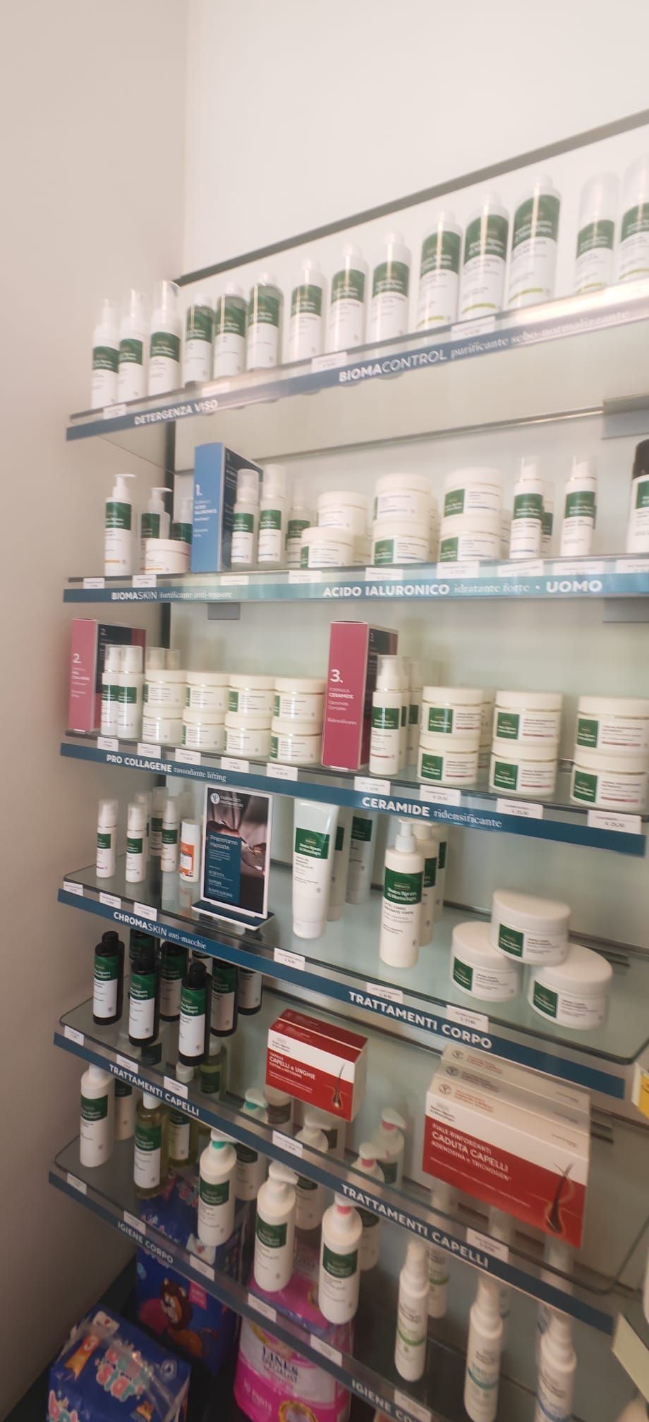 Scaffali pieni di flaconi di medicinali e prodotti farmaceutici di vario genere in una corsia di un negozio.