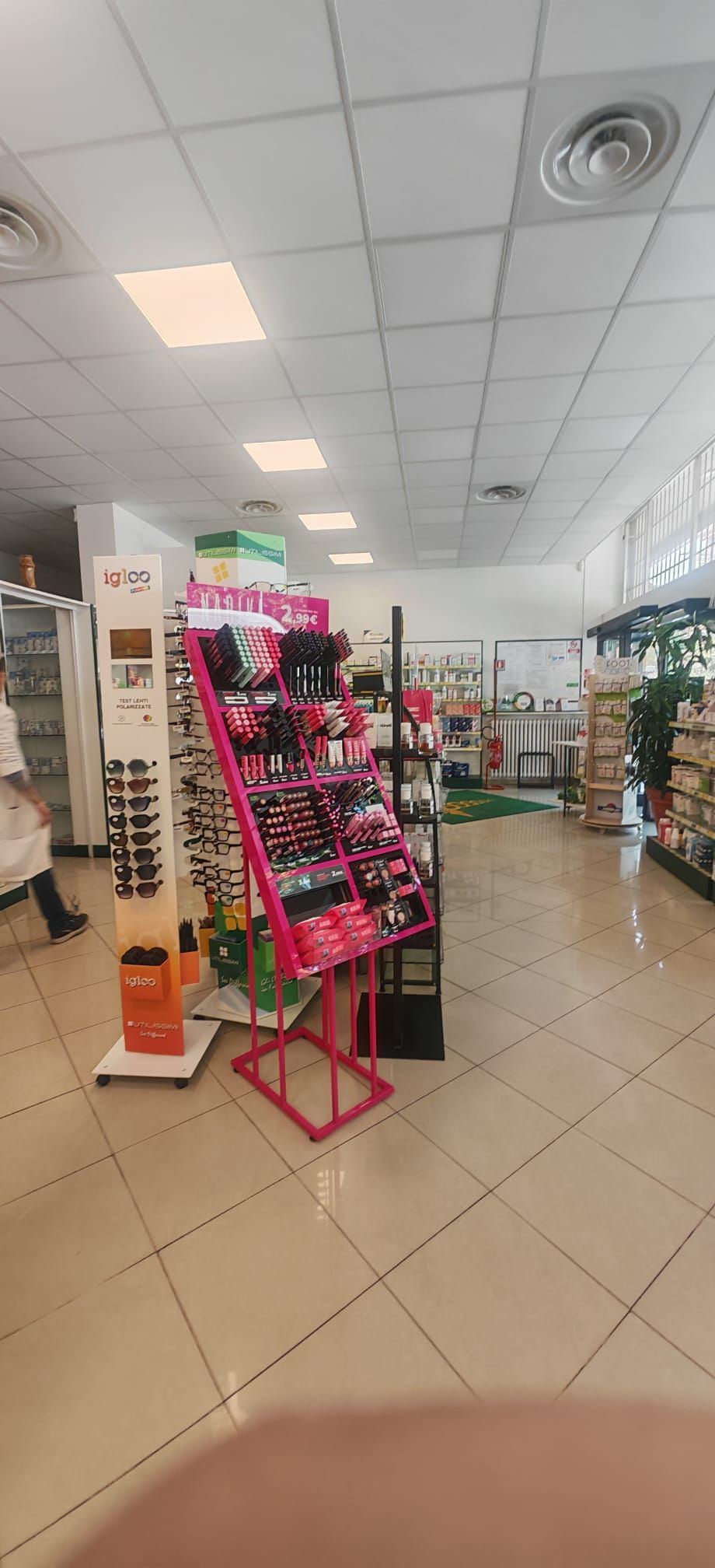 Corridoio di un negozio al dettaglio con espositore rosa, scaffali di prodotti e luci a soffitto.