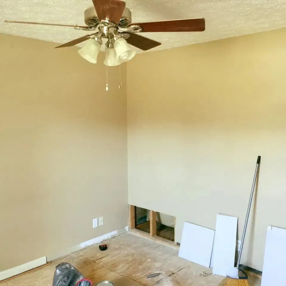 An empty room with a ceiling fan hanging from the ceiling