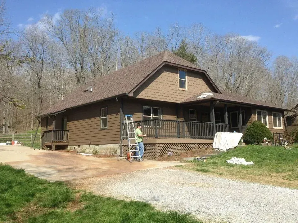 A man is standing on a ladder in front of a house.