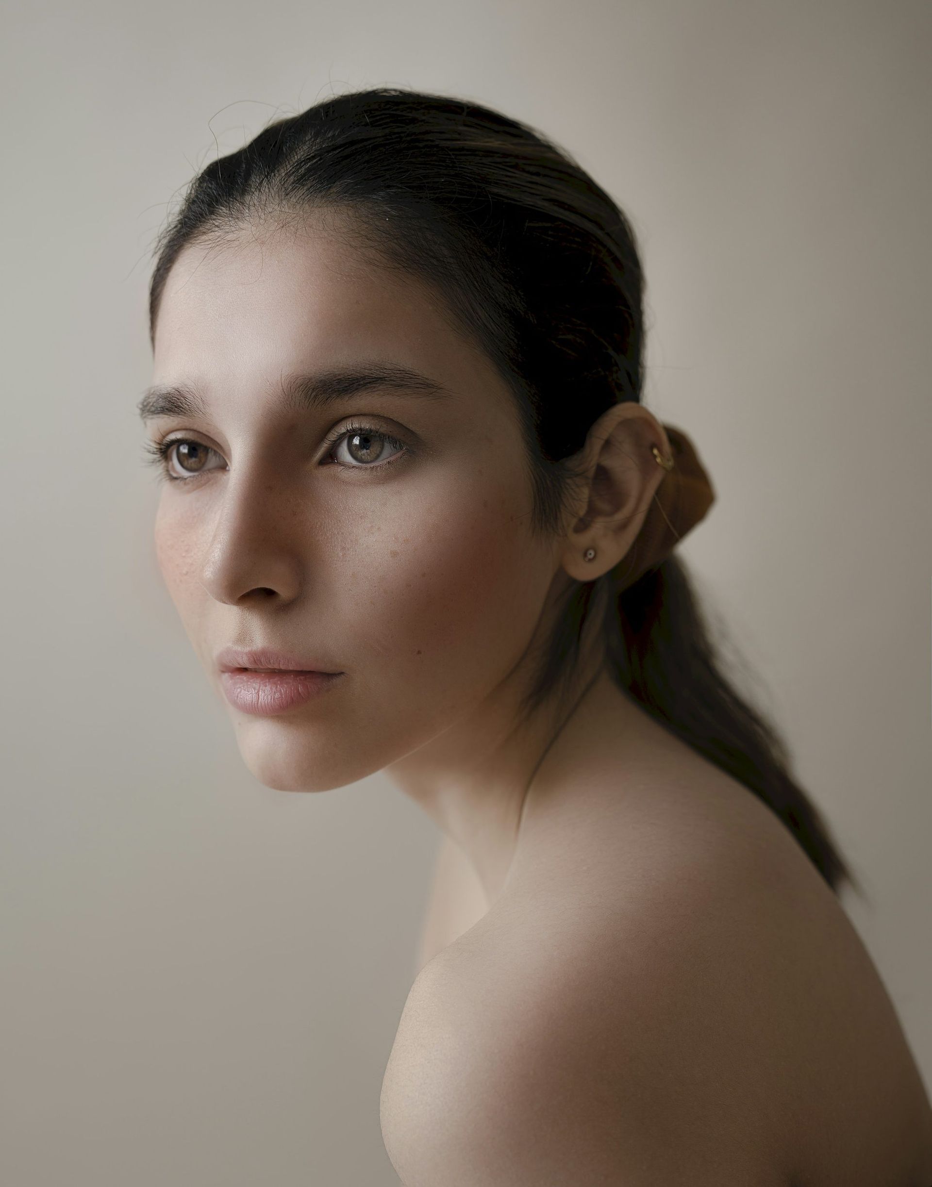 A profile beauty portrait on a warm neutral ground at MAX MD Medical Aesthetics and Wellness in Garden City, NY