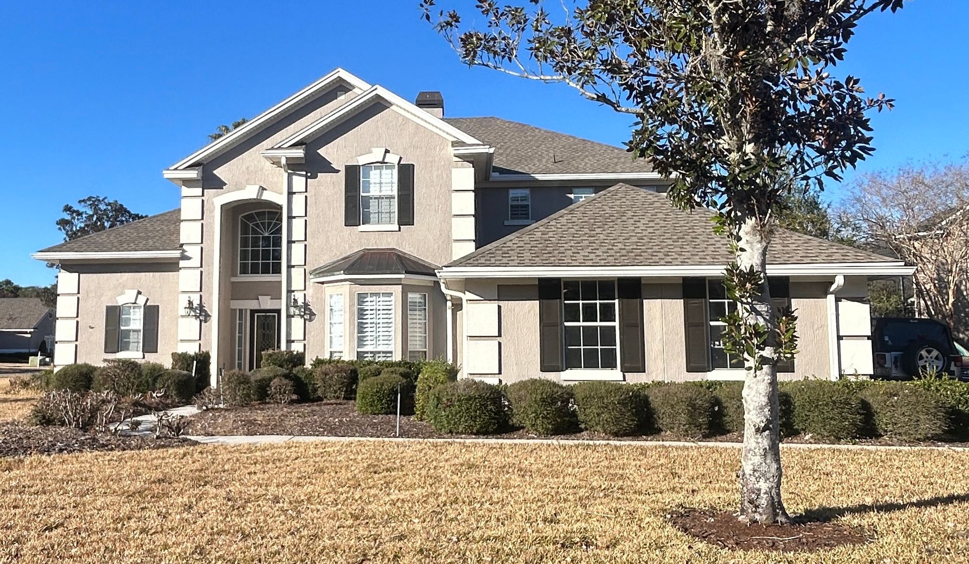 White-framed windows on a dark blue building, a small evergreen tree in front.