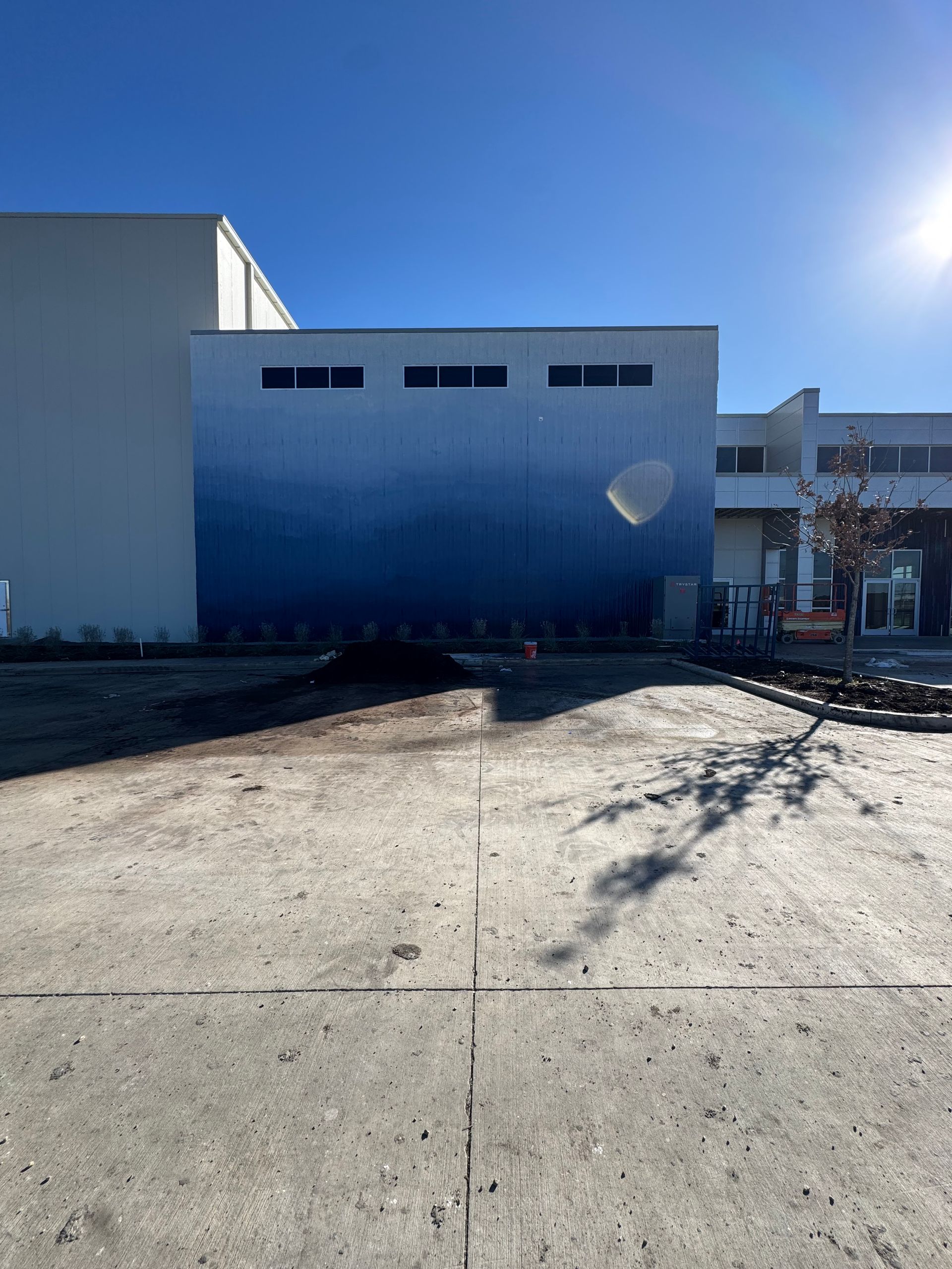 Hand painting a stucco wall with a roller; exterior shot, daylight.
